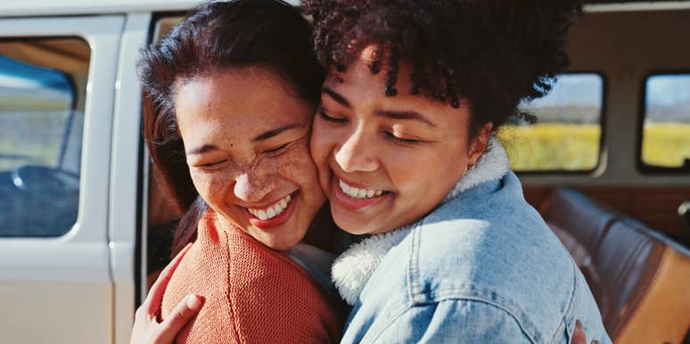 two women who have deep respect for each other hugging outside a car 