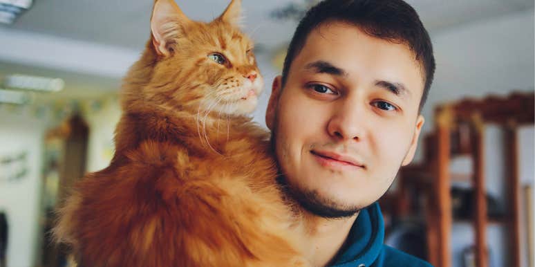 A big orange cat perches comfortably on his shoulder, the easy trust of a truly bonded pair.