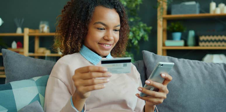 young woman holding credit card and phone to spend money