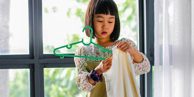 little girl folding and putting away her clothes in tidy home