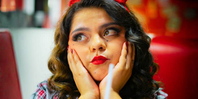 Woman in a retro diner setting gazes upward in thought, piecing together a memory from years working there.