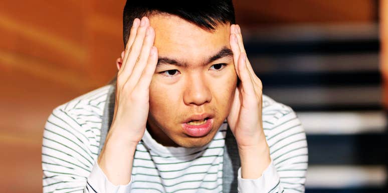 Man presses his hands to his temples, the visible stress of a relationship he knows he should've left.