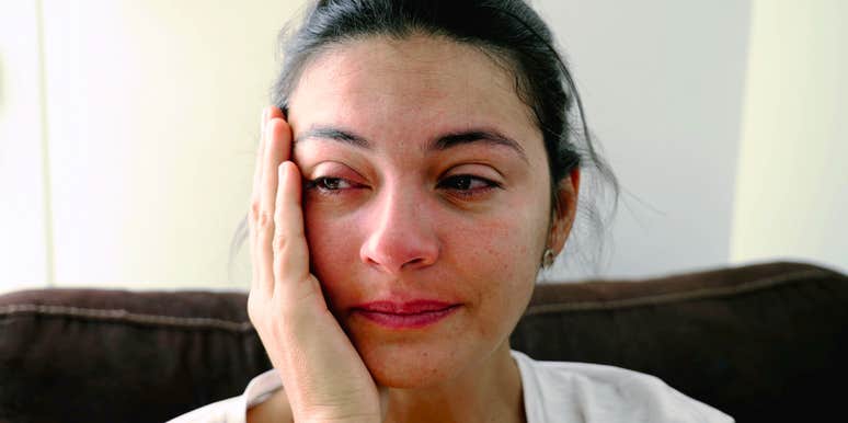 Woman crying quietly, resting head on hand, reflecting the exhaustion of caregiving