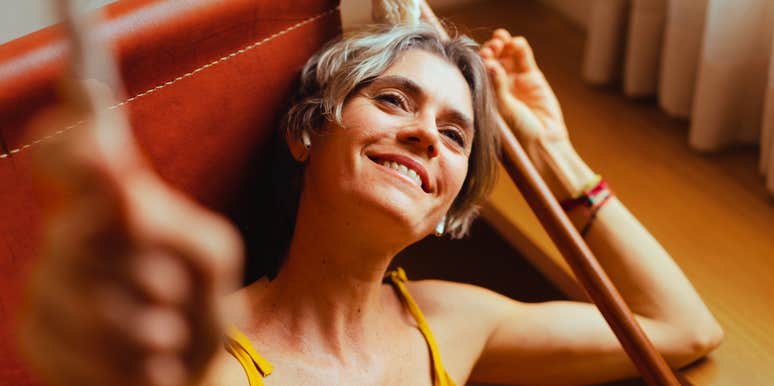 Woman lounges alone at home with a contented smile, at ease in her own company.