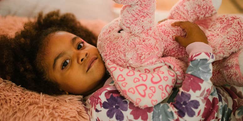 child snuggling with stuffed animal in bed but having no adult help
