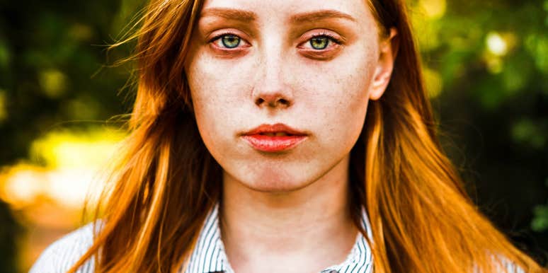 Woman with red hair looking stoically at camera. 