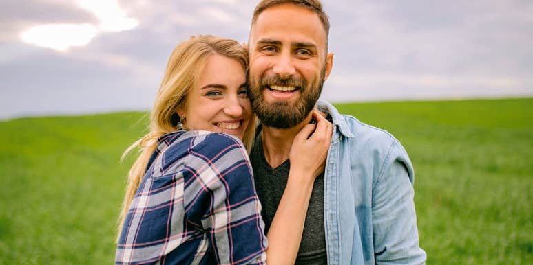 deeply happy couple hugging and smiling in a field