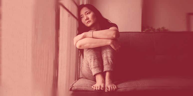 3 Common Thinking Errors That Sabotage Your Chance At Happiness woman looks sad, sitting against the wall