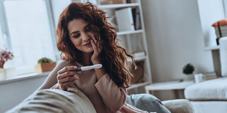 7 Signs You're Extremely Fertile (So Watch Out!) woman looking at pregnancy test