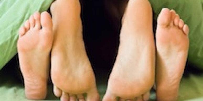 Feet at the foot of the bed under sheets