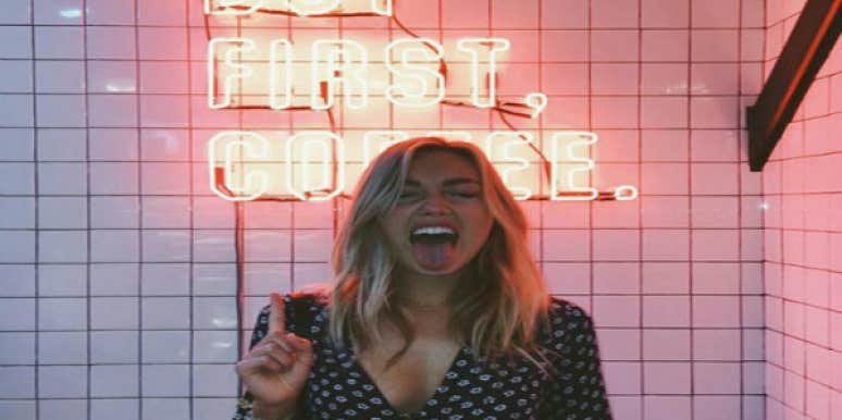 But First Coffee. Blonde woman with neon sign behind her.