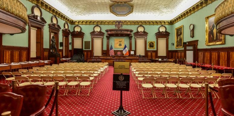 NYC Students Protest School Policing By Surprising City Council Meeting With Silence empty room where the NYC city council usually meets, filled with empty chairs and empty dais