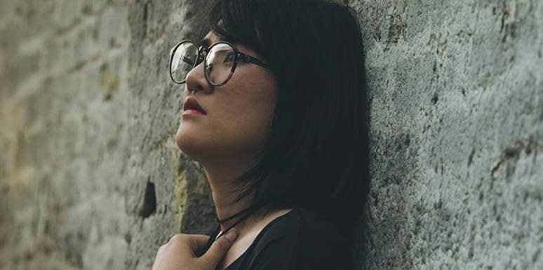 woman looking sad leaning against brick wall