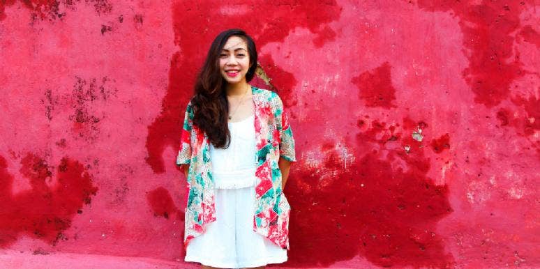 When Is Aries Season? How Each Zodiac Sign's Horoscope Will Be Affected woman in floral shirt standing in front of red wall
