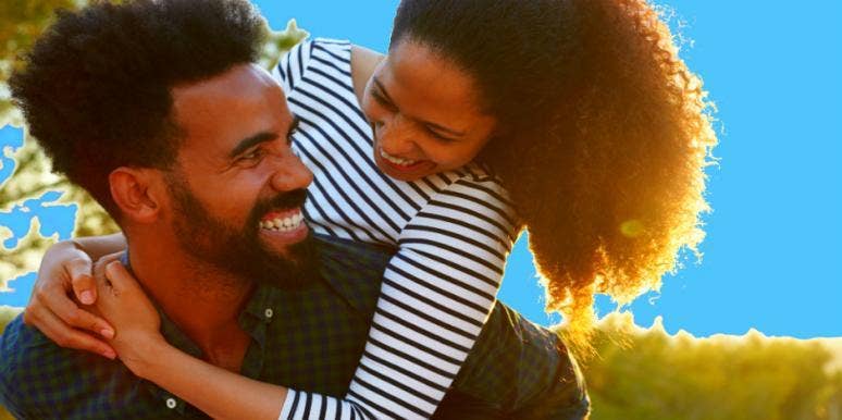 how to be a better boyfriend attractive Black couple snuggles playfully in front of a vibrant blue background