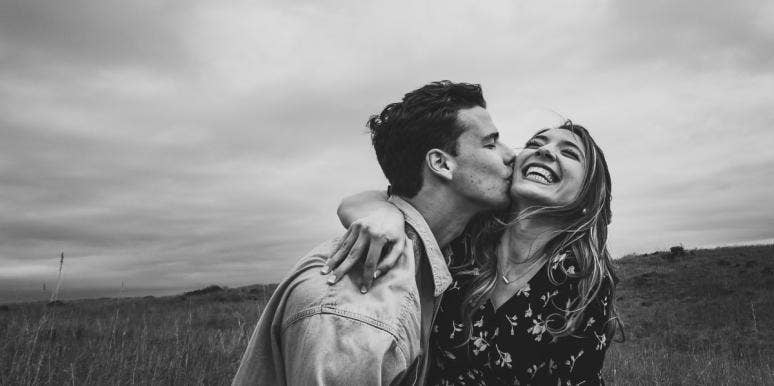 black and white photo of couple kissing in a field
