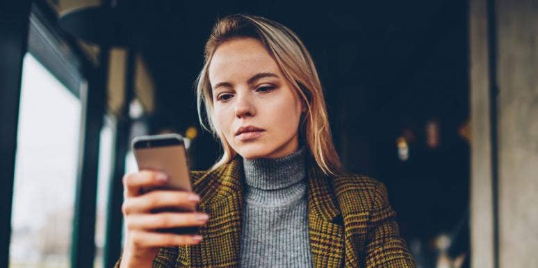 young woman looks critically at her phone, reading a conspiracy theory