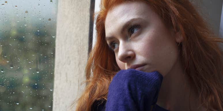redhaired woman looking out a window