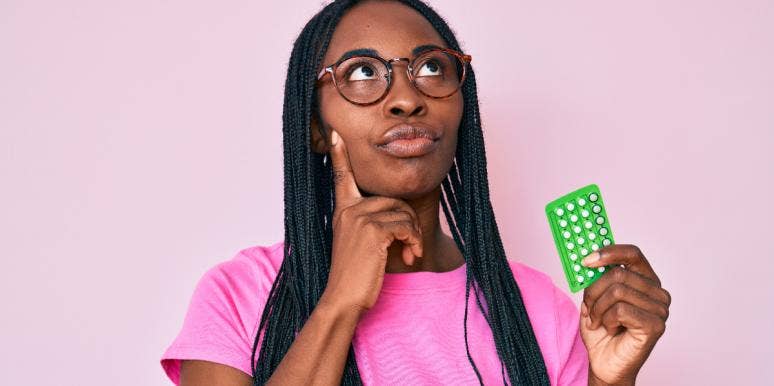 10 Surprising Facts About Birth Control (That You Probably Didn't Know) contemplative woman holding birth control pills