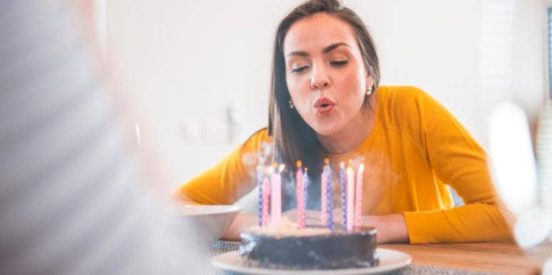 woman blowing out candles on a cake