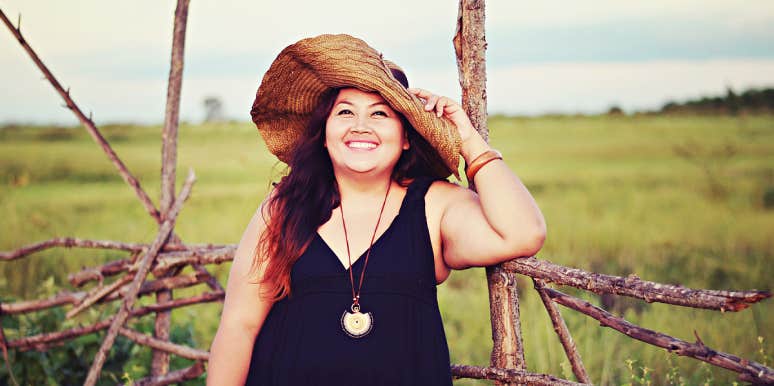 beautiful plus-size Asian woman smiling in a field in a big sun hat
