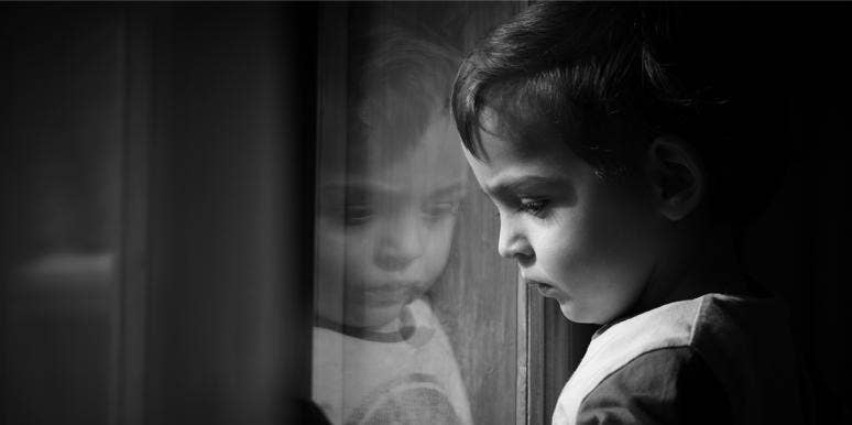 photo of child looking out window in black and white