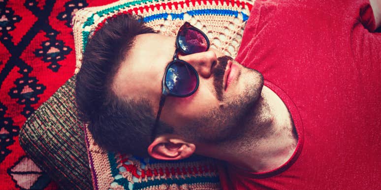 handsome man with mustache and sunglasses reclines on blanket