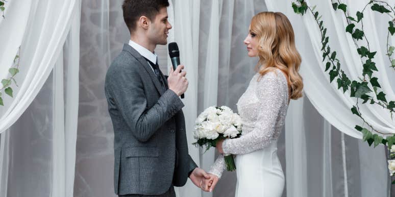 groom holding bride's hand and giving speech