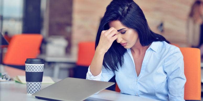 woman stressed head on hand in front of laptop