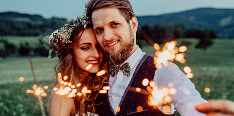 man and woman in wedding clothes holding sparklers 