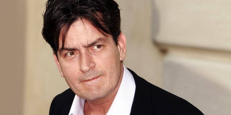 photo of Charlie Sheen in a suit and loose collar looking sideways at camera