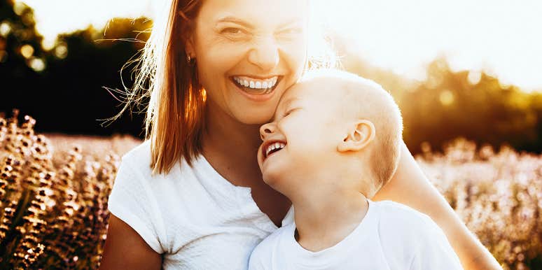 woman smiling in sunset, little boy laughing on her lap
