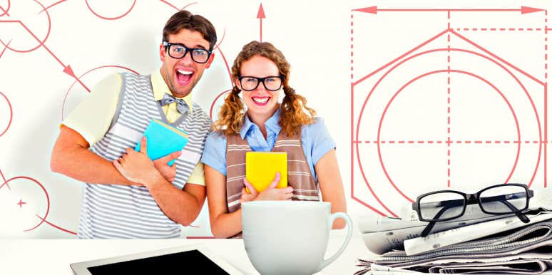 geeky hipster couple holding books and smiling at camera against blueprint