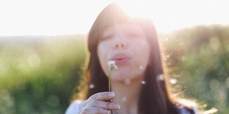 Clairsentient Meaning & Signs You Have This Rare Psychic Ability woman blowing on a dandelion