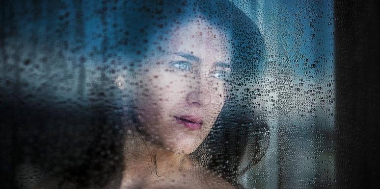 woman looking out a window at the rain