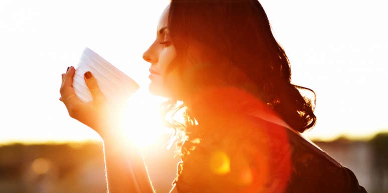 the veil between life and death Woman with sunrise behind her drinking tea, in profile
