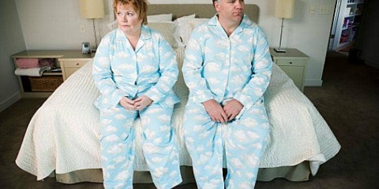 couple sitting on bed in matching pajamas couple sitting on bed in matching pajamas
