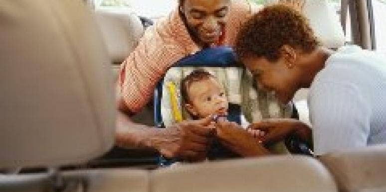 parents buckling a baby into a car seat