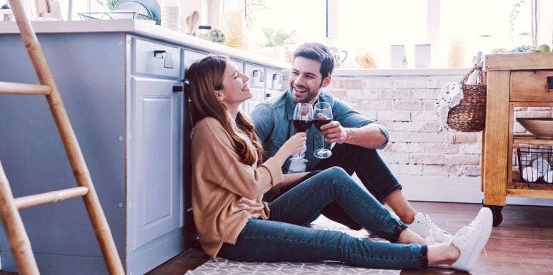 couples first house man and woman sitting on the floor of a kitchen drinking wine