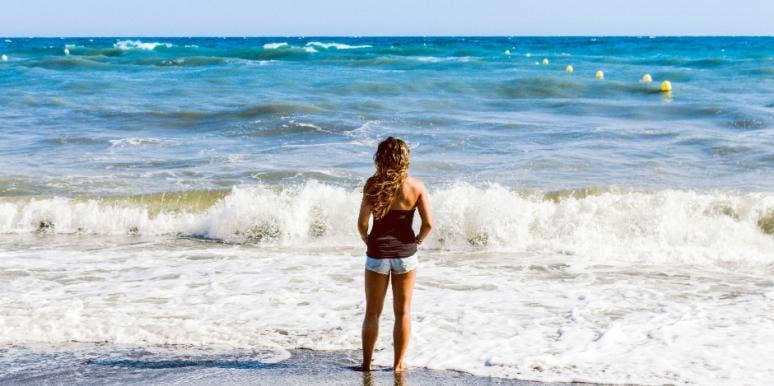 Girl standing facing water Girl standing facing water