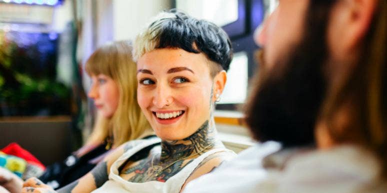smiling person with short hair and tattoos