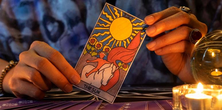 What Is The Difference Between Oracle Cards And Tarot Cards? Person holding the Sun tarot card