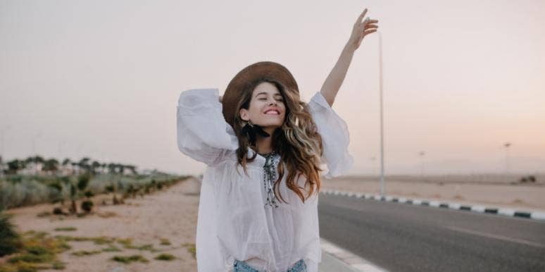 Why You Shouldn’t Be Afraid To Experience Life Alone happy woman with arm up at beach