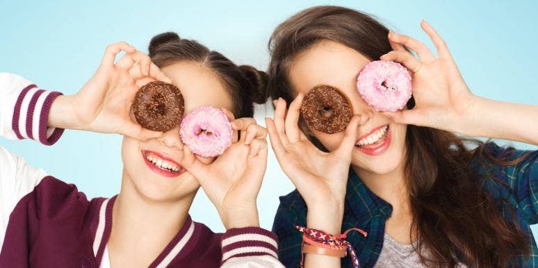 two girls holding donuts up to their eyes