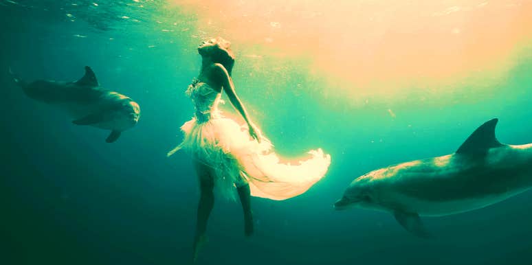 woman dreaming about being under water surrounded by dolphins
