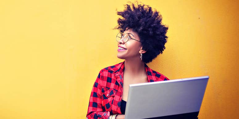 Woman with natural hair smiles confidently against yellow background
