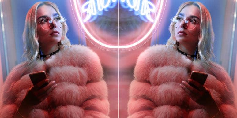 Fierce Zodiac Signs, Ranked From Most Savage To Softest woman in glasses and fuzzy jacket in front of neon sign