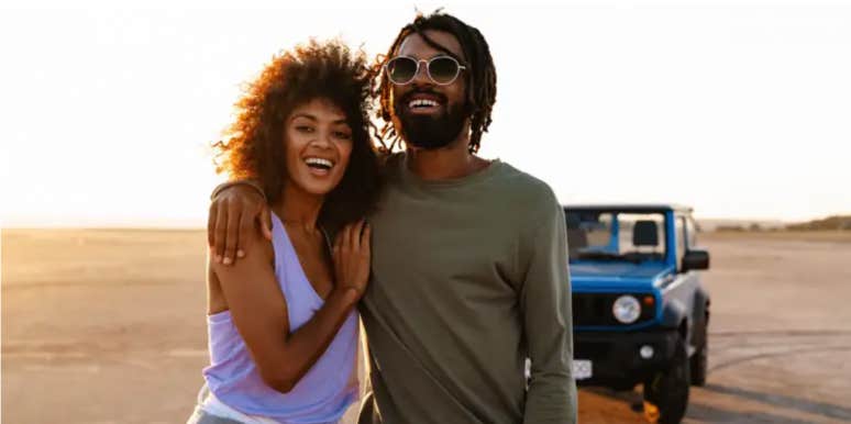 couple walking together, cuddling, in the desert in front of a blue jeep