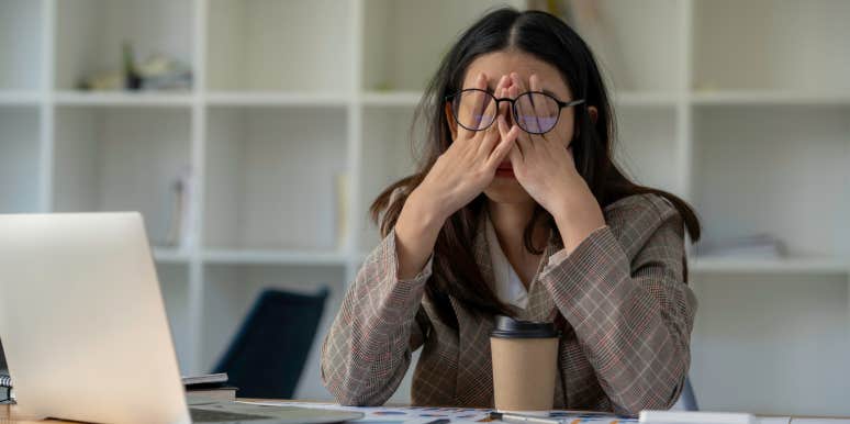 Frustrated employee holds her head in front of computer.