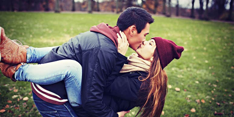 Couple outdoors in cool weather, playing around and kissing